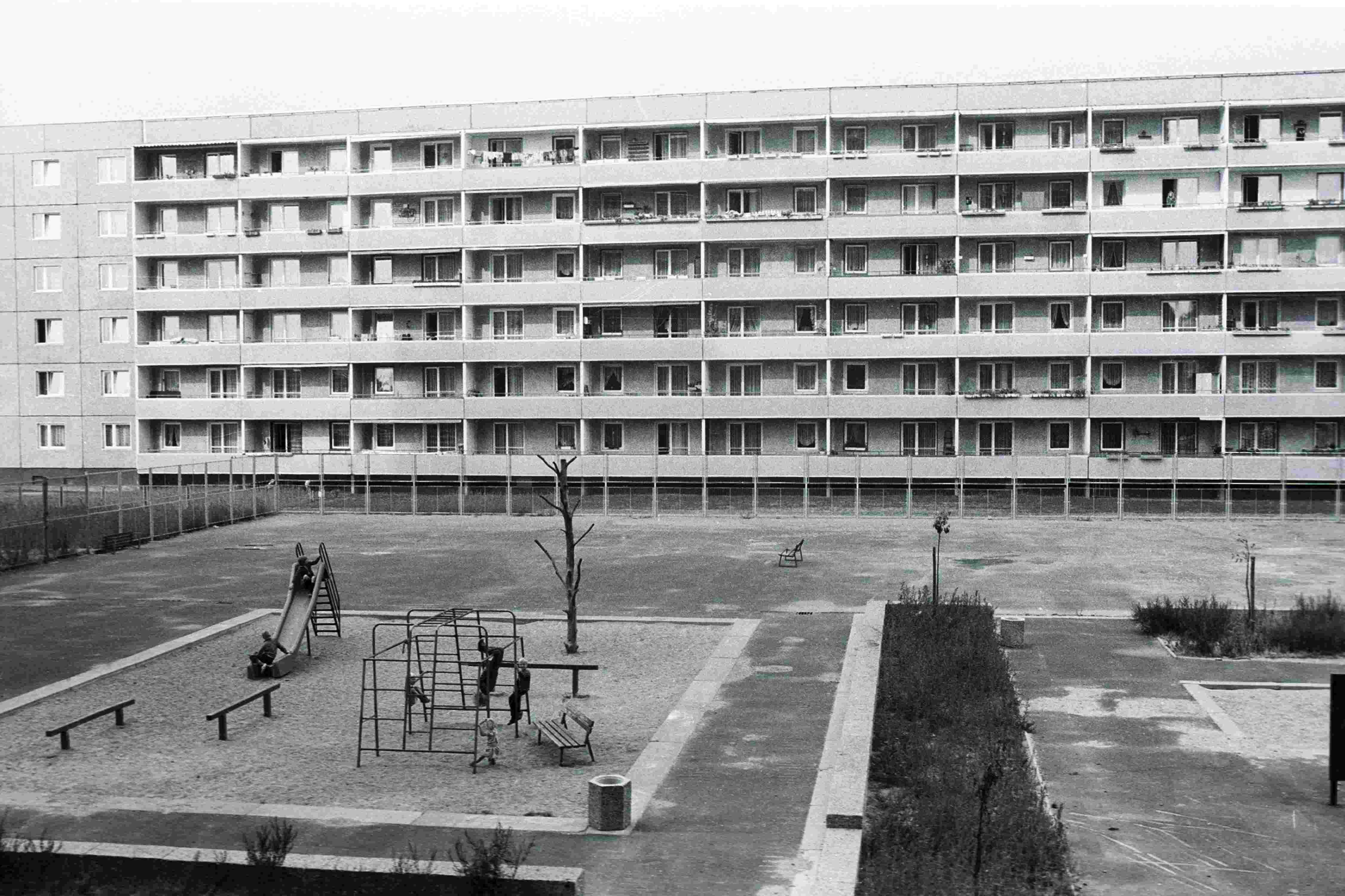 Schwarz-Weiß-Bild eines Spielplatzes aus der Vogelperspektive inmitten von Plattenbauten in der Joseph-Orlopp-Straße in Berlin-Lichtenberg zu DDR-Zeiten