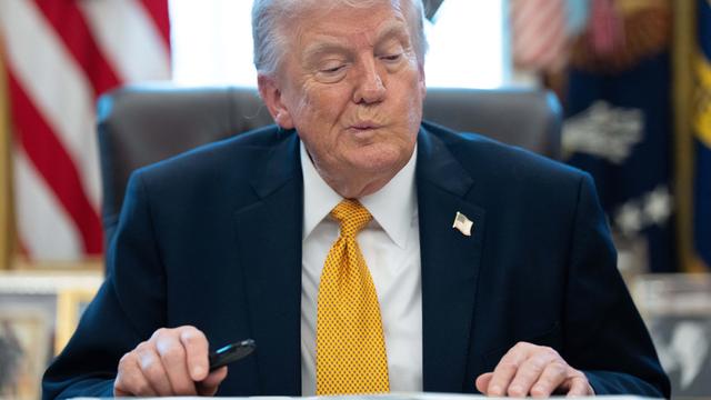 US-Präsident Trump sitzt im Weißen Haus an einem Schreib-Tisch. Er macht ein nachdenkliches Gesicht.