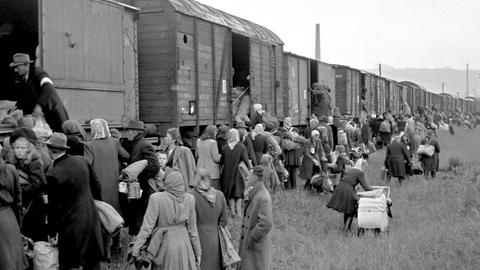 Hunderte Menschen mit Kinderwagen und schweren Taschen steigen in einen Güterzug ein. Am 16. Mai 1946 werden deutsche Familien aus Prag am Bahnhof Modrany aus der Tschecheslowakei abtransportiert.