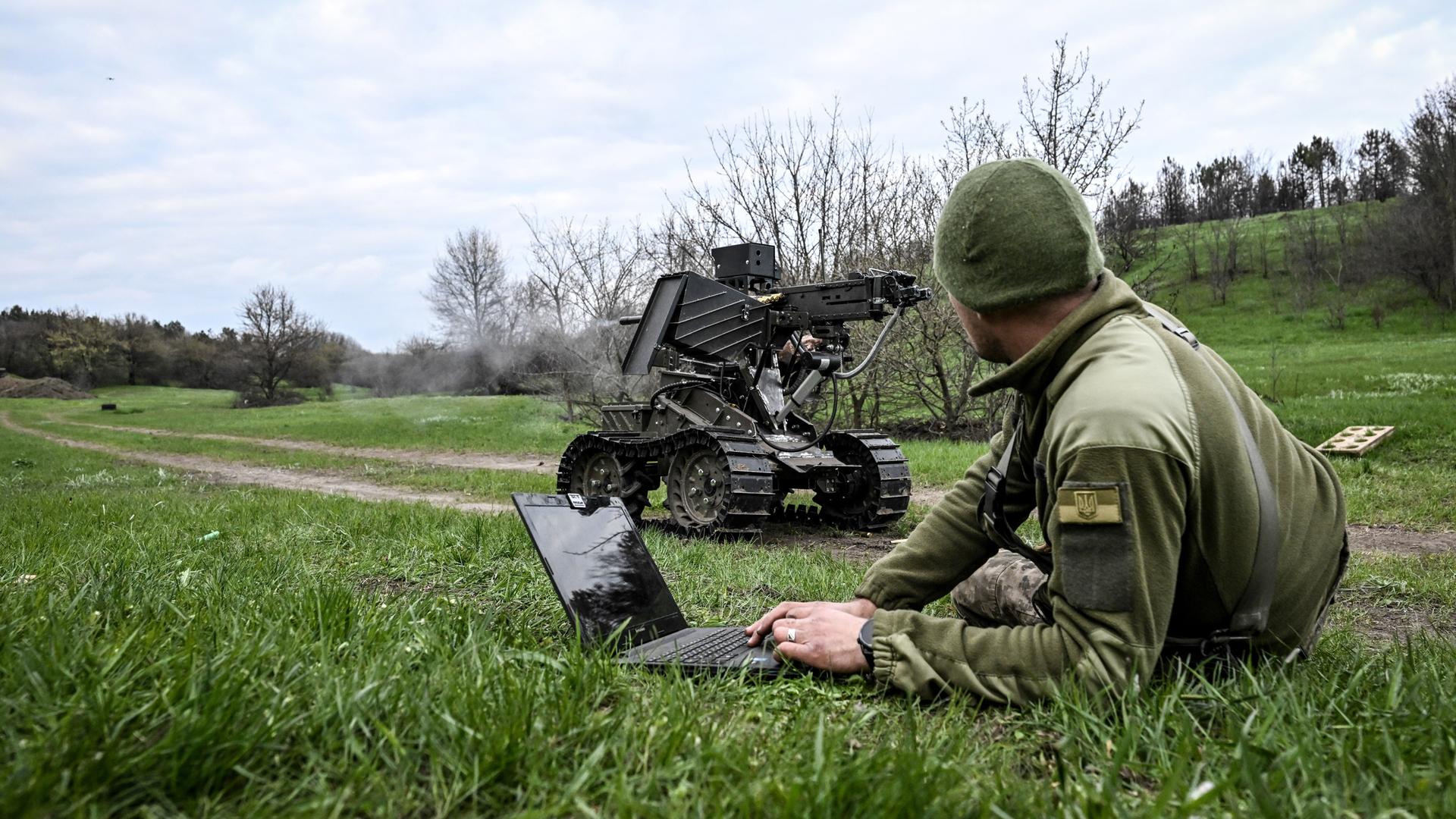 Ein Soldat bedient mit dem Laptop ein Roboterfahrzeug, auf das ein Maschinengewehr montiert wurde. Ein Soldat bedient mit dem Laptop ein Roboterfahrzeug, auf das ein Maschinengewehr montiert wurde.