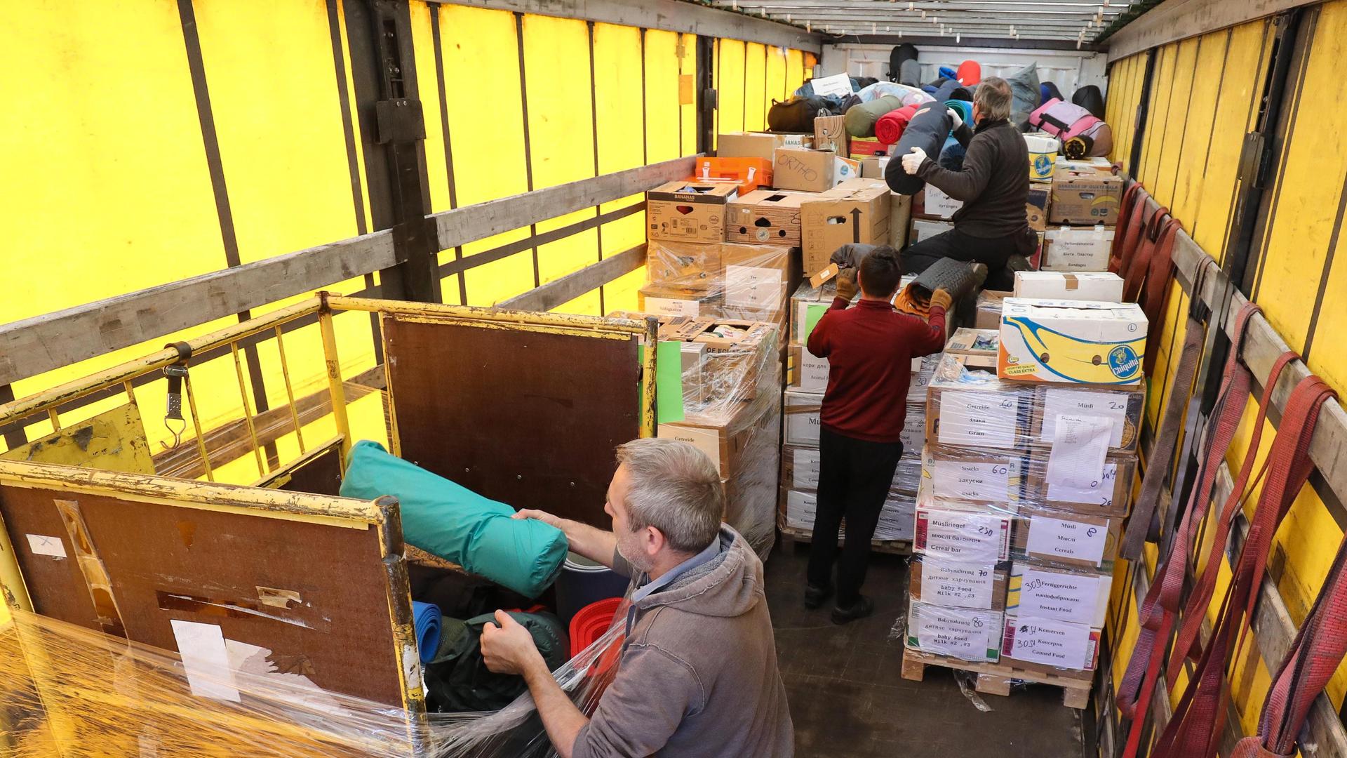 Auf der Ladefläche eines LKW verladen Freiwillige Spendengüter für die Ukraine.