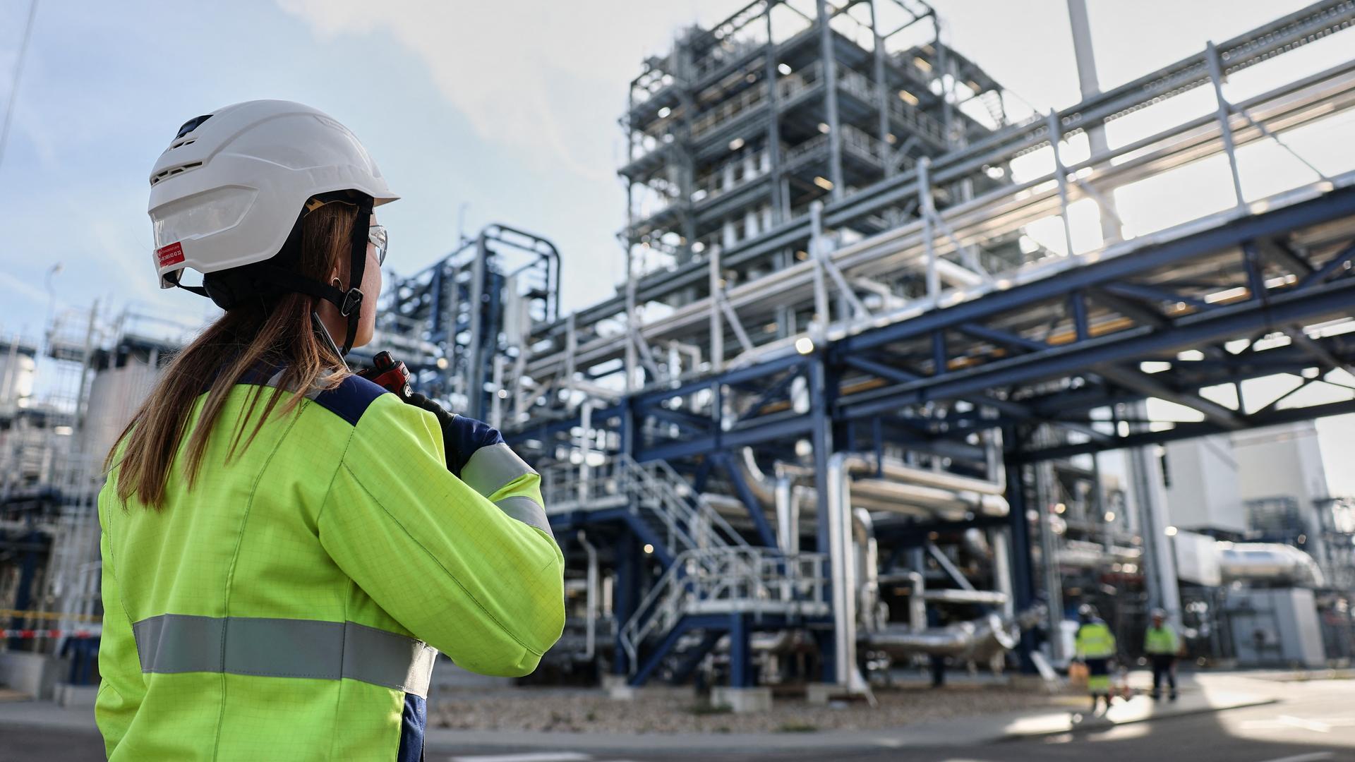 Eine Mitarbeiterin der UPM-Bioraffinerie Leuna spricht in ihr Funkgerät. Im Hintergrund sieht man das Chemiewerk. Eine Mitarbeiterin der UPM-Bioraffinerie Leuna spricht in ihr Funkgerät. Im Hintergrund sieht man das Chemiewerk.
