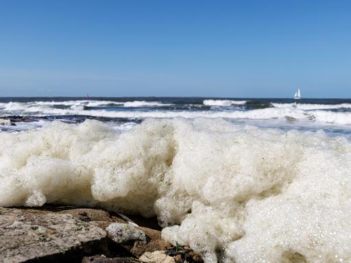 Wellen spülen Schaum an den Strand der ostfriesischen Insel Norderney Wellen spülen Schaum an den Strand der ostfriesischen Insel Norderney