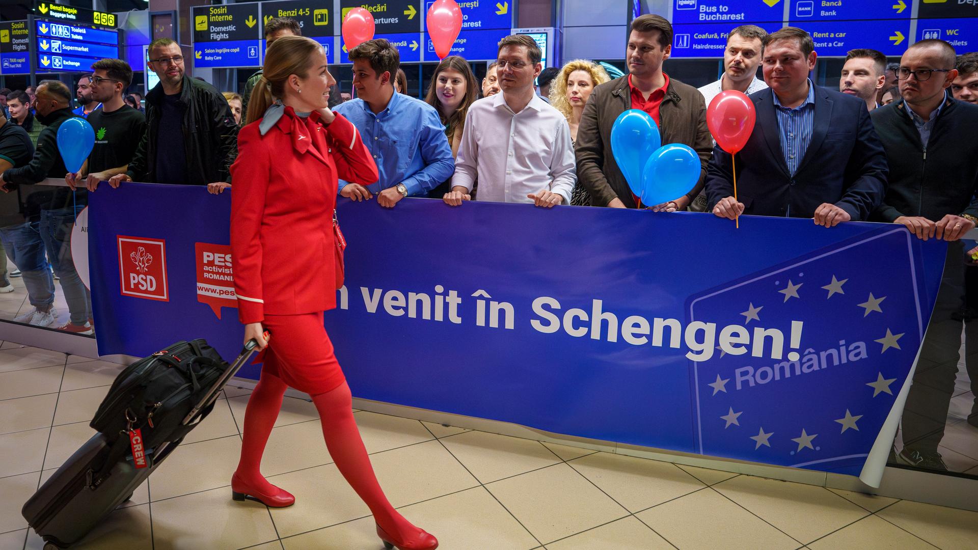 Eine Flugbegleiterin geht an einem Schild mit der Aufschrift "Willkommen in Schengen" vorbei, als sie am Sonntag, 31. März 2024, auf dem internationalen Flughafen Henri Coanda in Otopeni in der Nähe von Bukarest, Rumänien, ankommt.