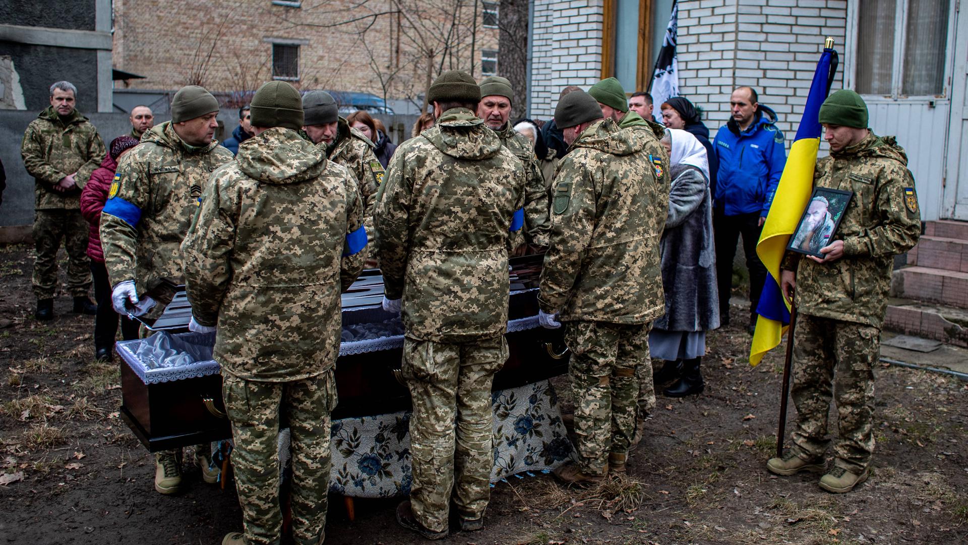 Ukrainische Soldaten halten Mahnwache an einem Sarg im Freien.