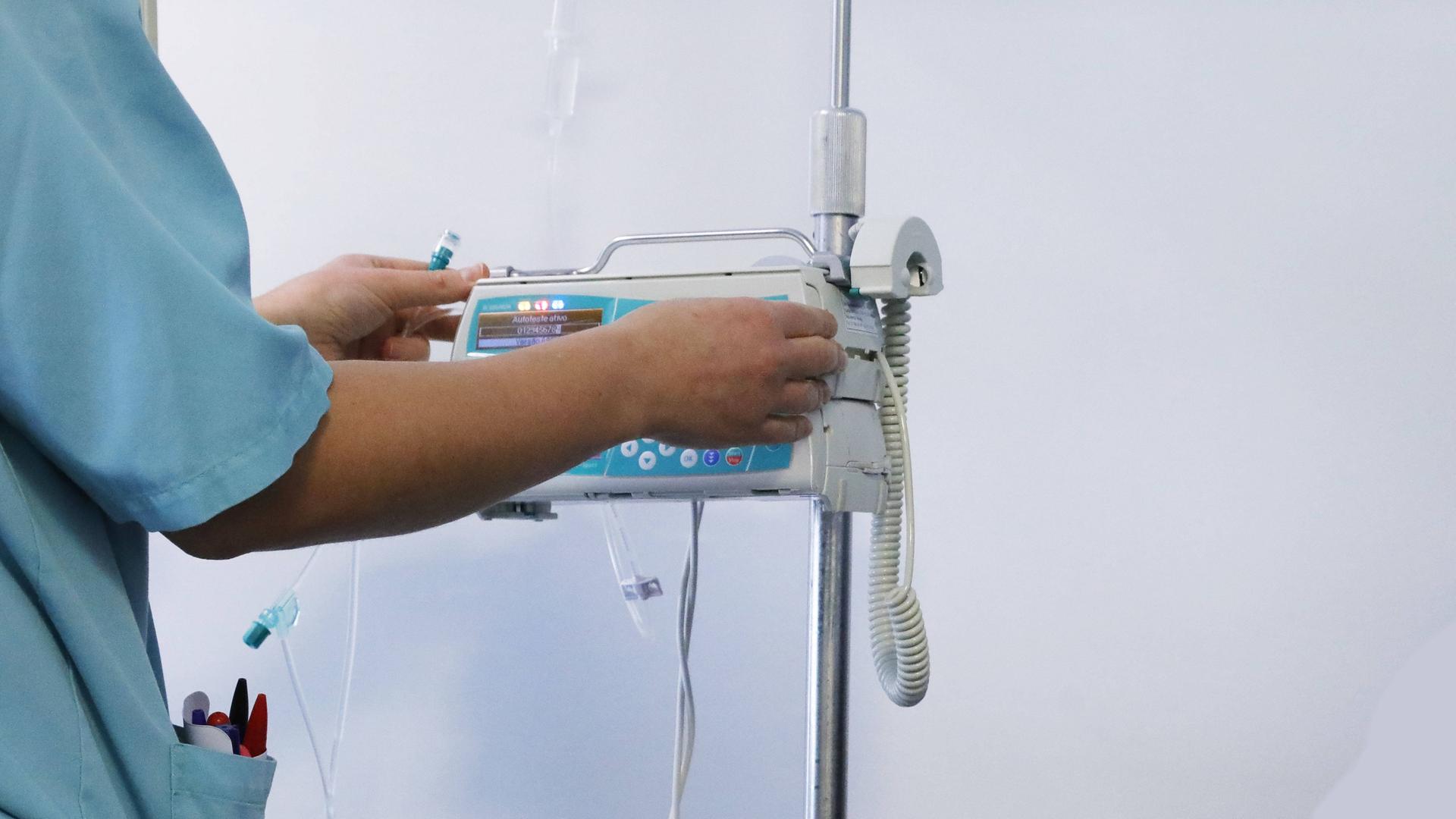 Pflegepersonal steht an einem Gerät und bedient es. Pflegepersonal steht an einem Gerät und bedient es.