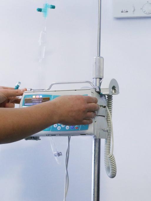 Pflegepersonal steht an einem Gerät und bedient es.