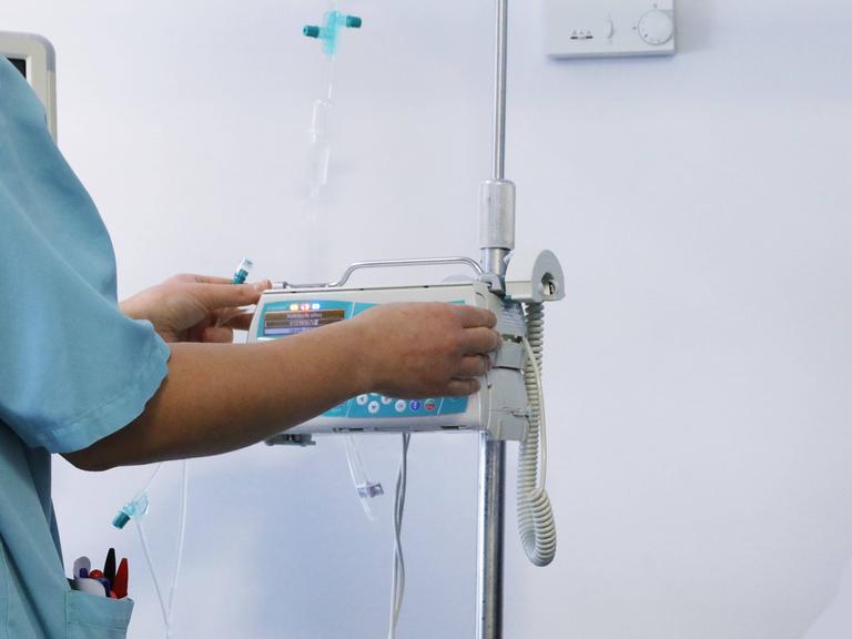 Pflegepersonal steht an einem Gerät und bedient es.