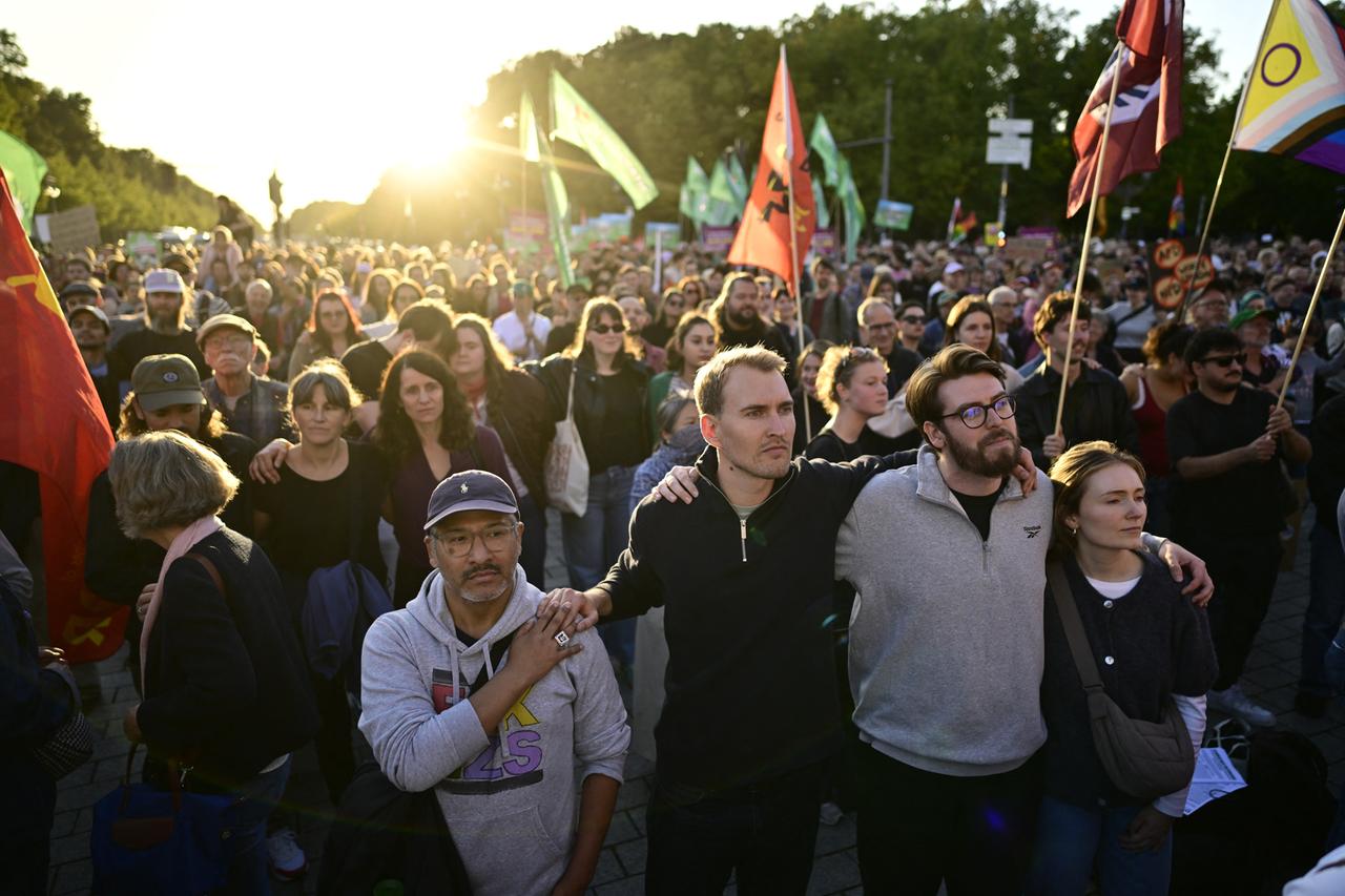 Menschen stehen mit Fahnen am Brandenburger Tor mit Blick auf die Siegessäule während einer Kundgebung gegen die AfD.
