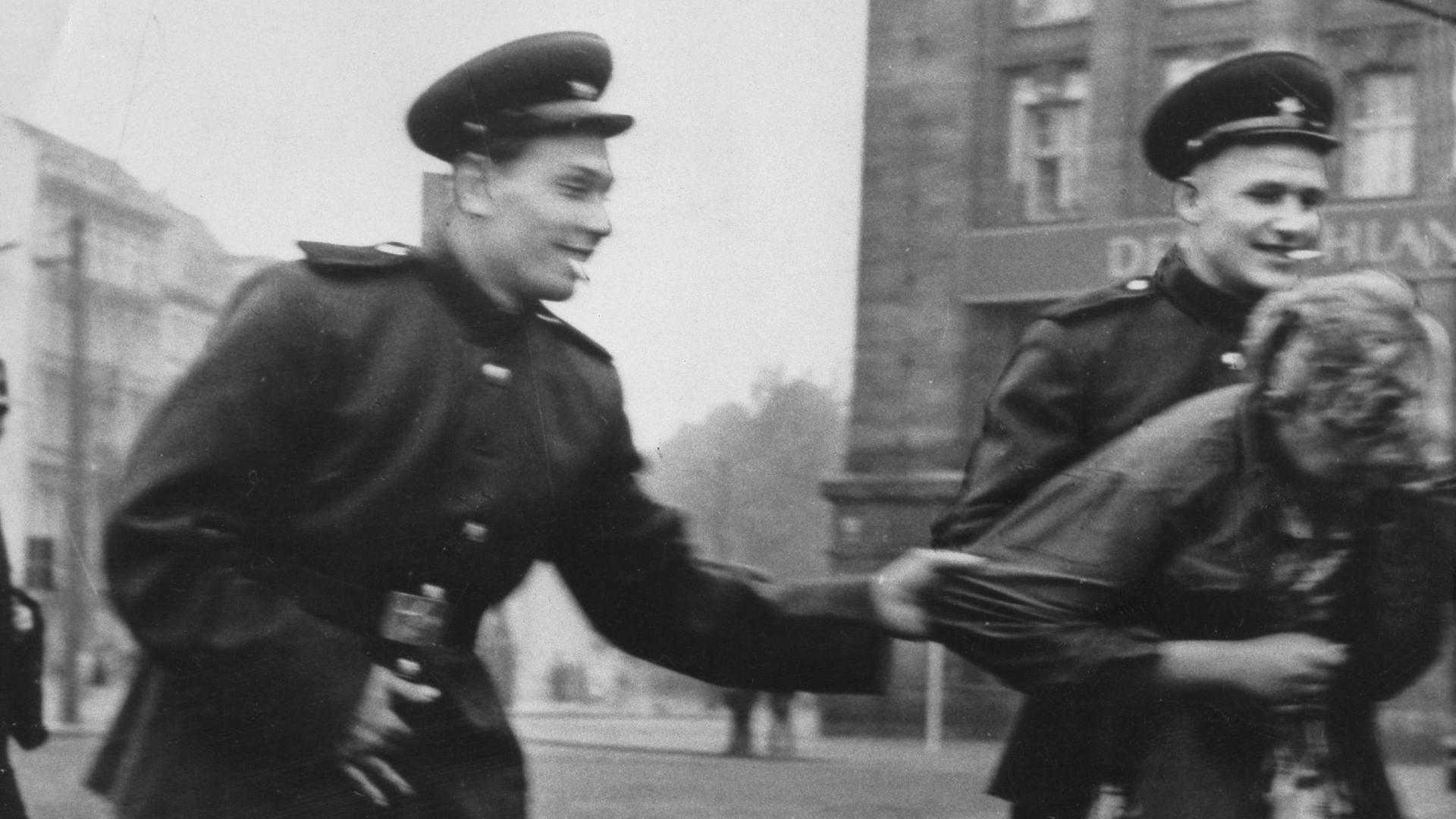 Historisches Schwarzweißfoto von zwei sowjetische Soldaten, die auf der Straße in Leipzig eine Passantin belästigen. Historisches Schwarzweißfoto von zwei sowjetische Soldaten, die auf der Straße in Leipzig eine Passantin belästigen.