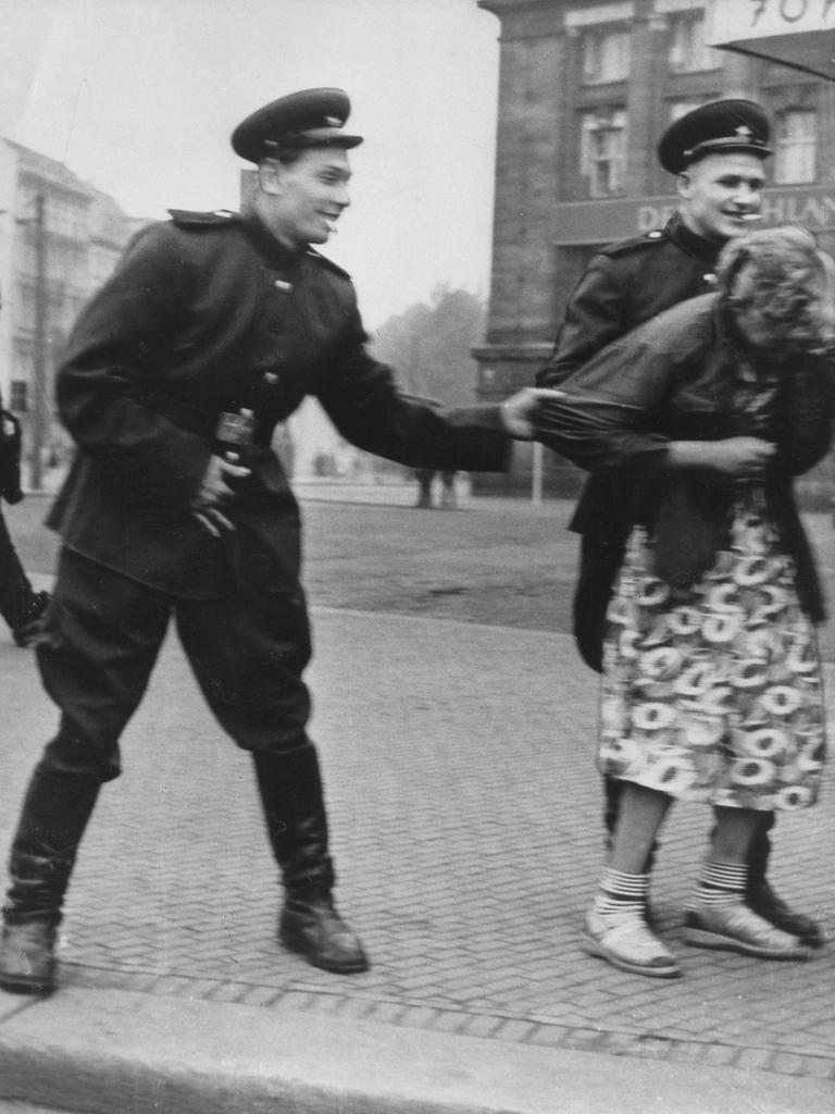 Historisches Schwarzweißfoto von zwei sowjetische Soldaten, die auf der Straße in Leipzig eine Passantin belästigen.