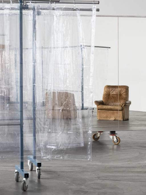 Blick in das experimentelle Live-Kunstwerk „Scalable Skeletal Escalator“ der in Berlin lebenden Künstlerin Isabel Lewis in der Kunsthalle Zürich, Schweiz. Sichtbar sind Folien als Raumtrenner und ein Sessel.