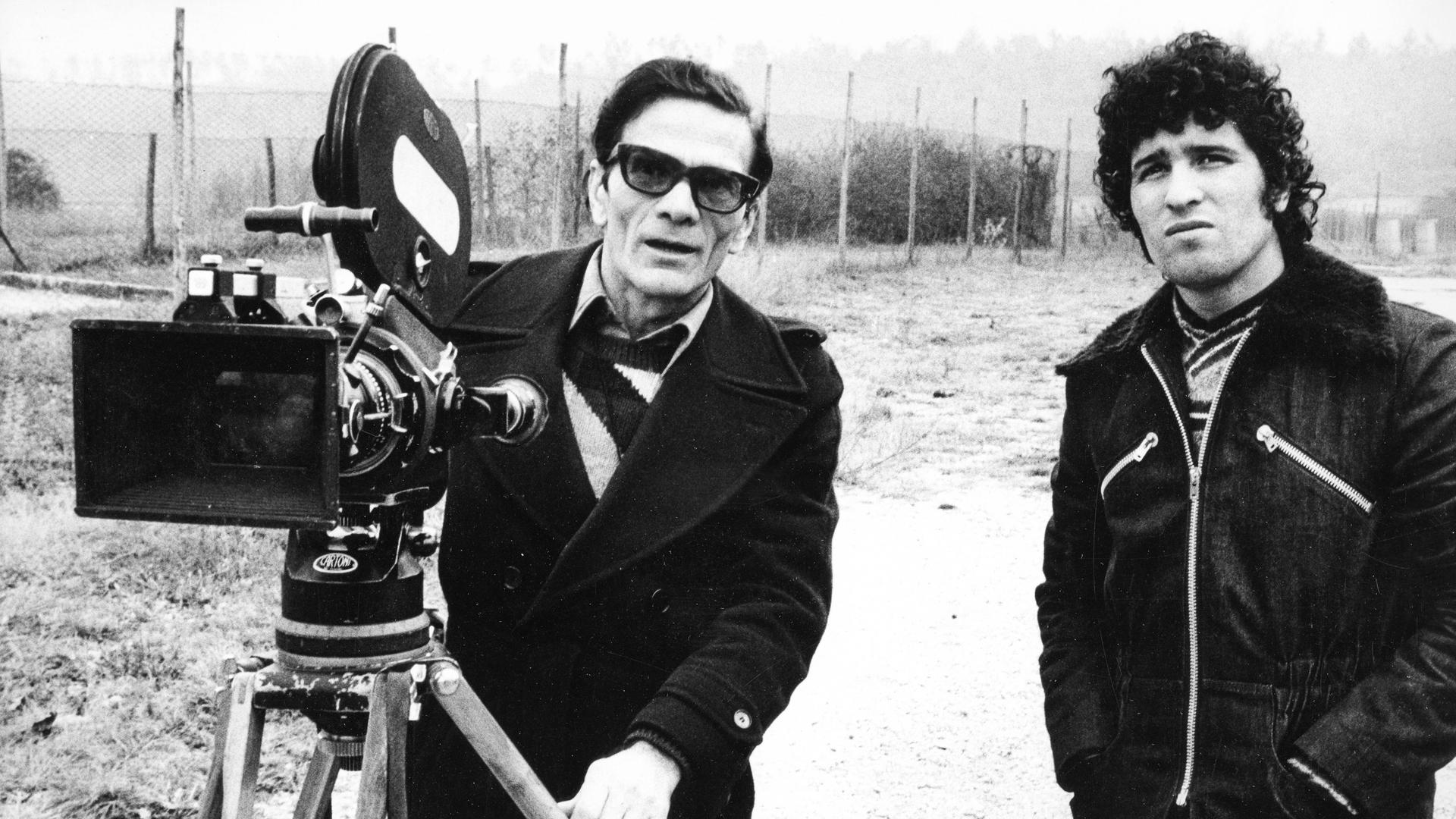 Pier Paolo Pasolini und Ninetto Davoli stehen an einem Filmset hinter der Kamera. Pier Paolo Pasolini und Ninetto Davoli stehen an einem Filmset hinter der Kamera.