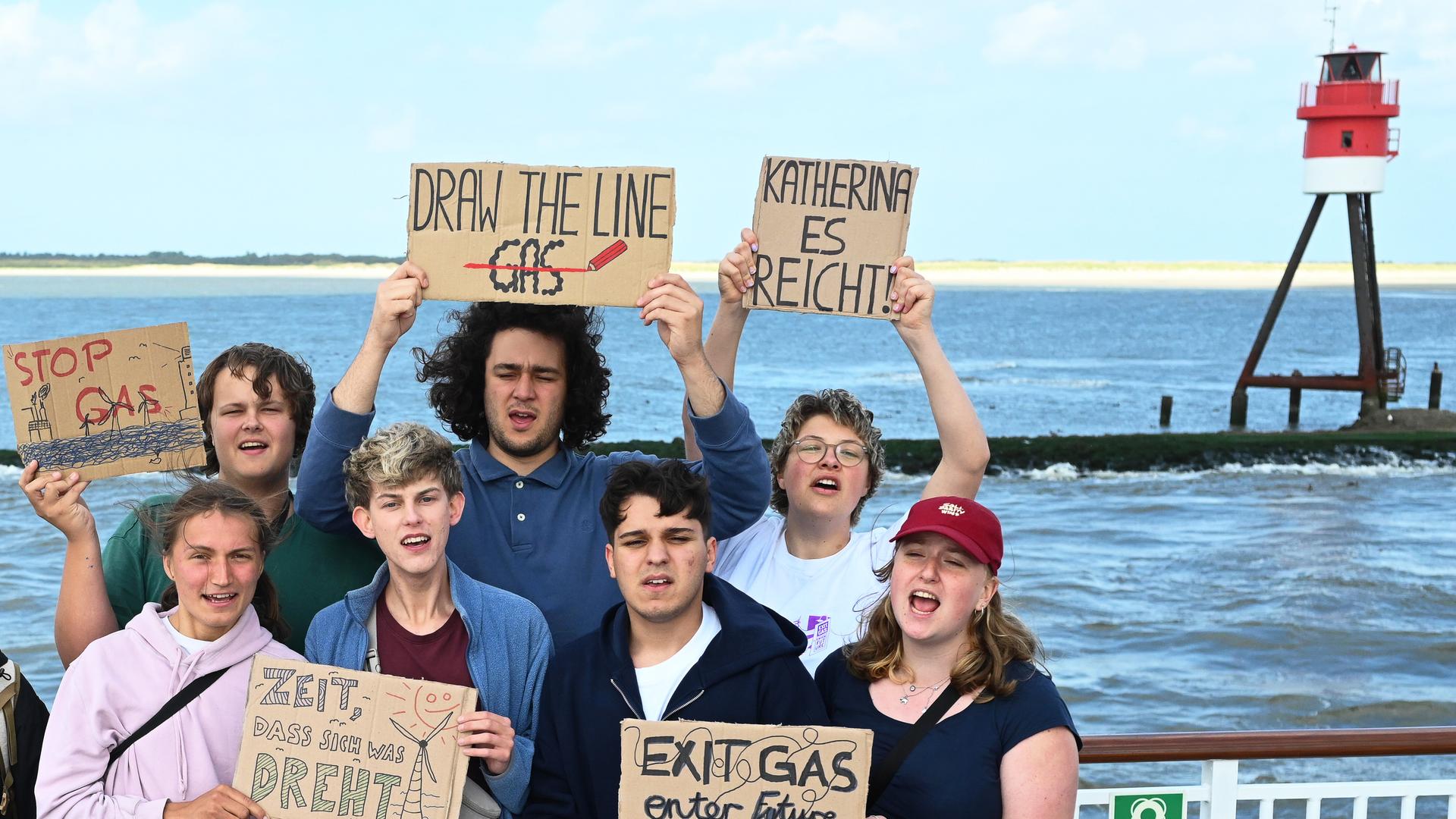 Aktivisten der Klimabewegung Fridays for Future halten Protestschilder während der Fahrt mit der Fähre nach Borkum. Sie wollen in den kommenden Tagen auf Borkum erneut gegen die Erdgasförderung in der Nordsee nahe der Insel demonstrieren.