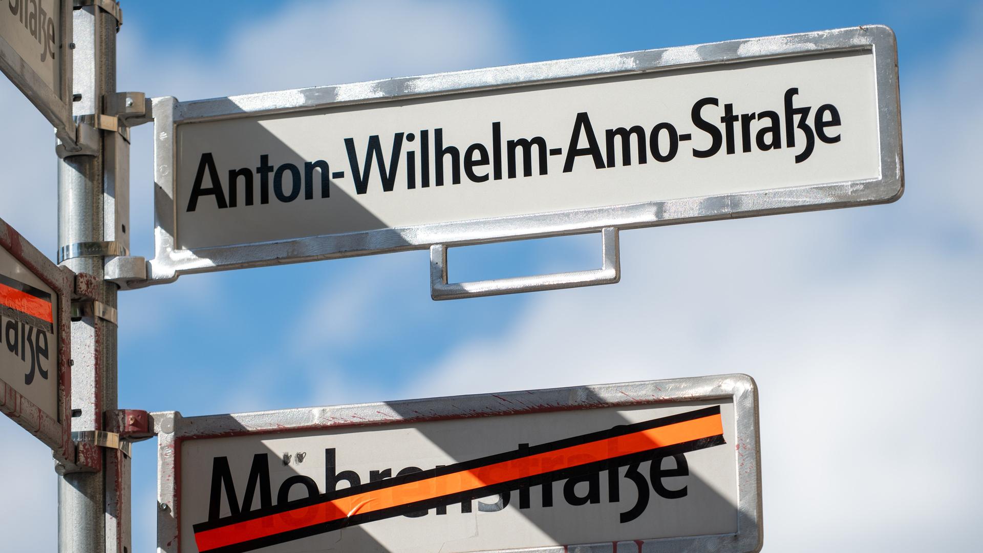 Ein Schild mit der Aufschrift Anton-Wilhelm-Amo-Straße hängt über einem Schild, auf dem der Name Mohrenstraße durchgestrichen ist Ein Schild mit der Aufschrift Anton-Wilhelm-Amo-Straße hängt über einem Schild, auf dem der Name Mohrenstraße durchgestrichen ist