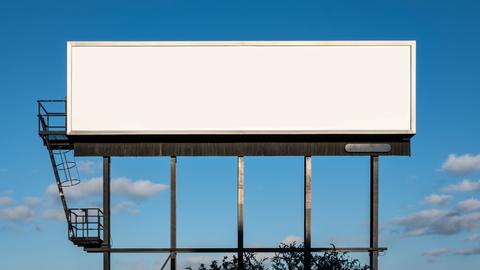 Ein leeres weißes Billboard vor einem blauen Himmel.