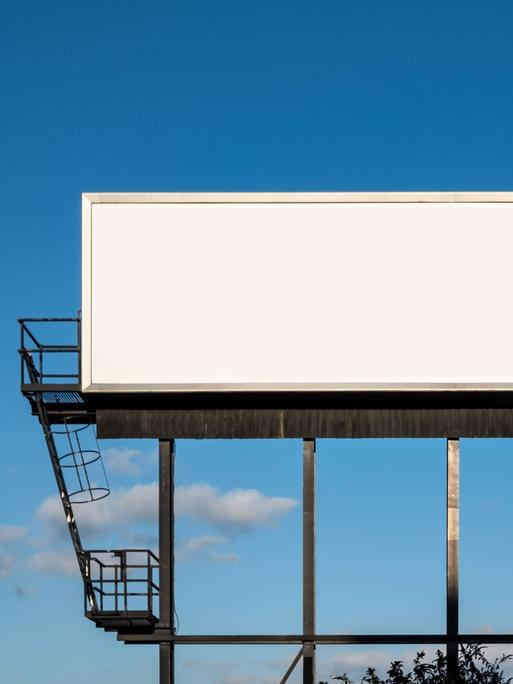 Ein leeres weißes Billboard vor einem blauen Himmel.