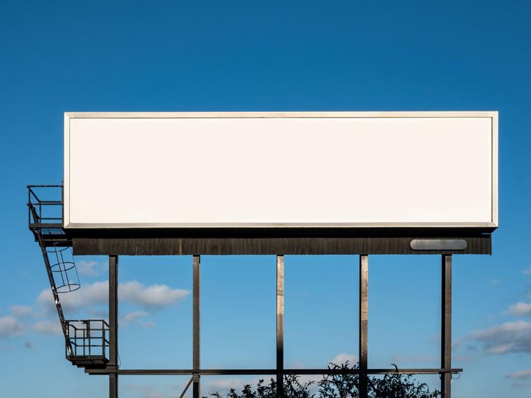 Ein leeres weißes Billboard vor einem blauen Himmel.