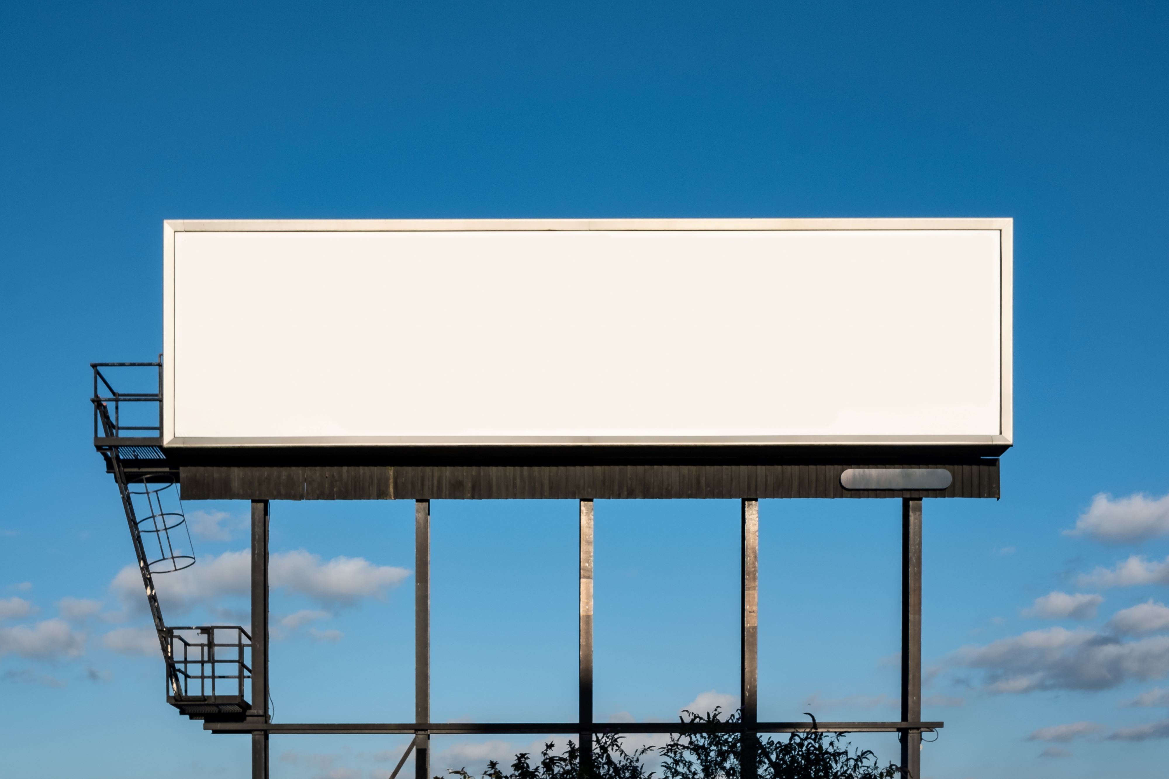 Ein leeres weißes Billboard vor einem blauen Himmel.