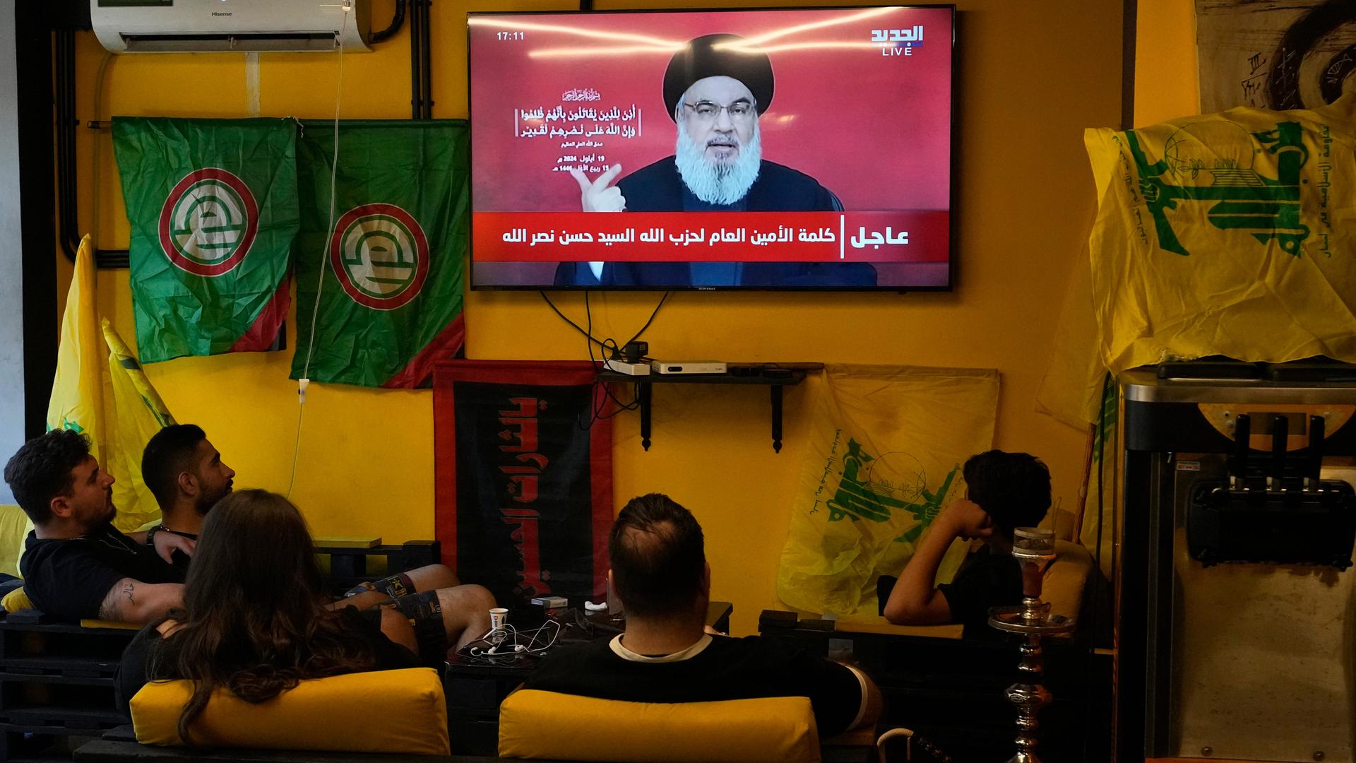 Menschen sitzen in Beirut vor einem TV-Gerät, auf dem eine Ansprache von Hassan Nasrallah übertragen wird.