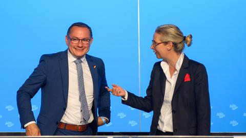 Die AfD-Politiker Tino Chrupalla und Alice Weidel stehen auf der Bühne nebeneinander.