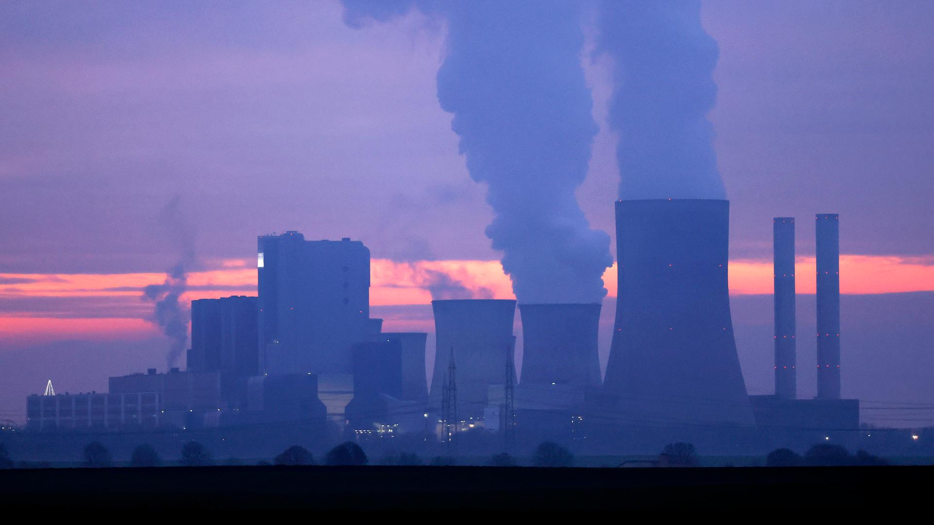 Türme eines Kohlekraftwerks stoßen Rauch aus in den abendlichen Himmel im Sonnenuntergang. Türme eines Kohlekraftwerks stoßen Rauch aus in den abendlichen Himmel im Sonnenuntergang.
