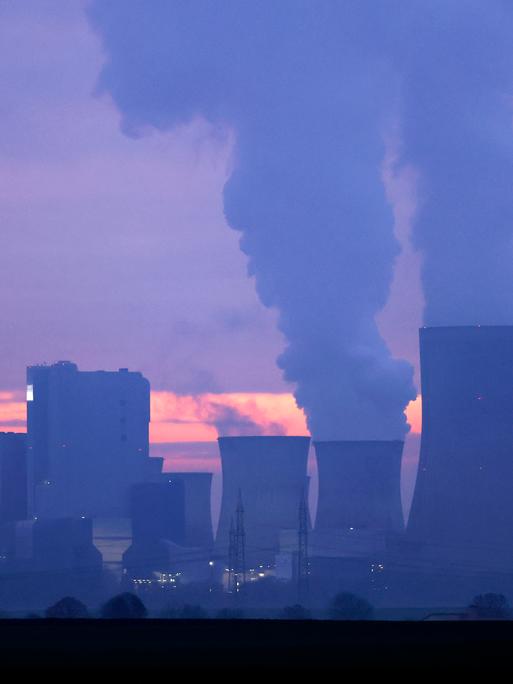 Türme eines Kohlekraftwerks stoßen Rauch aus in den abendlichen Himmel im Sonnenuntergang. Türme eines Kohlekraftwerks stoßen Rauch aus in den abendlichen Himmel im Sonnenuntergang.