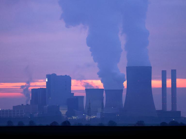Türme eines Kohlekraftwerks stoßen Rauch aus in den abendlichen Himmel im Sonnenuntergang. Türme eines Kohlekraftwerks stoßen Rauch aus in den abendlichen Himmel im Sonnenuntergang.