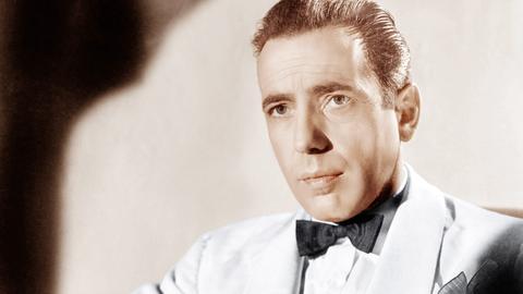 Humphrey Bogart im weißen Anzug und in lässig-cooler Pose.