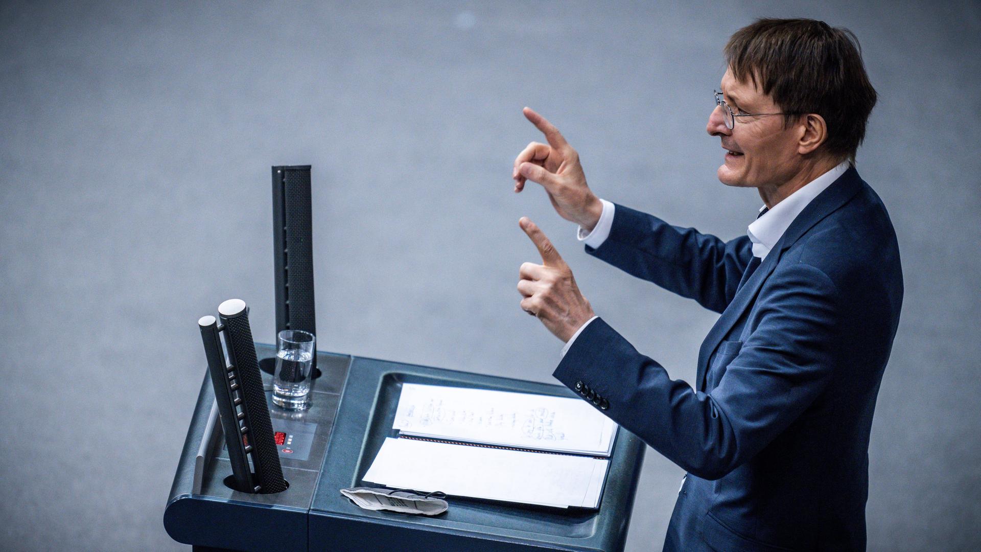 Karl Lauterbach steht am Redepult des Bundestags und sprich gestikulierend zu den Abgeordneten.