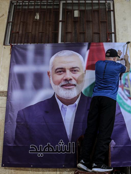 Ein Palästinenser hängt ein großes Foto des getöteten Hamas-Chefs Ismail Hanija im Flüchtlingslager Burj al-Brajneh auf.