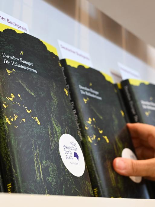 Eine Hand greift am Stand des Hanser Verlags auf der Frankfurter Buchmesse nach dem Buch der Schweizer Autorin Dorothee Elmiger mit dem Titel "Die Holländerinnen", dem Siegertitel beim Deutschen Buchpreis 2025. Eine Hand greift am Stand des Hanser Verlags auf der Frankfurter Buchmesse nach dem Buch der Schweizer Autorin Dorothee Elmiger mit dem Titel "Die Holländerinnen", dem Siegertitel beim Deutschen Buchpreis 2025.
