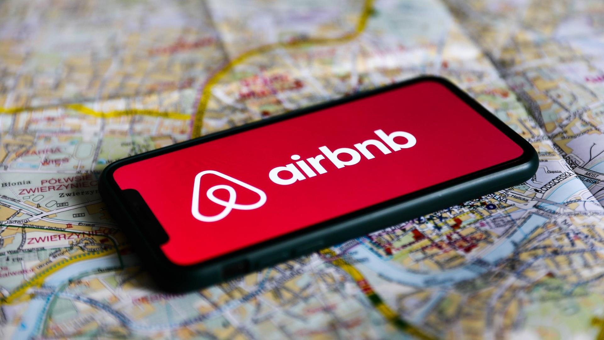 Airbnb-Logo liegt auf einer Landkarte.