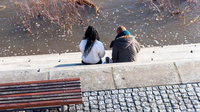 Zwei junge Frauen sitzen an der Elbe in Magdeburg.