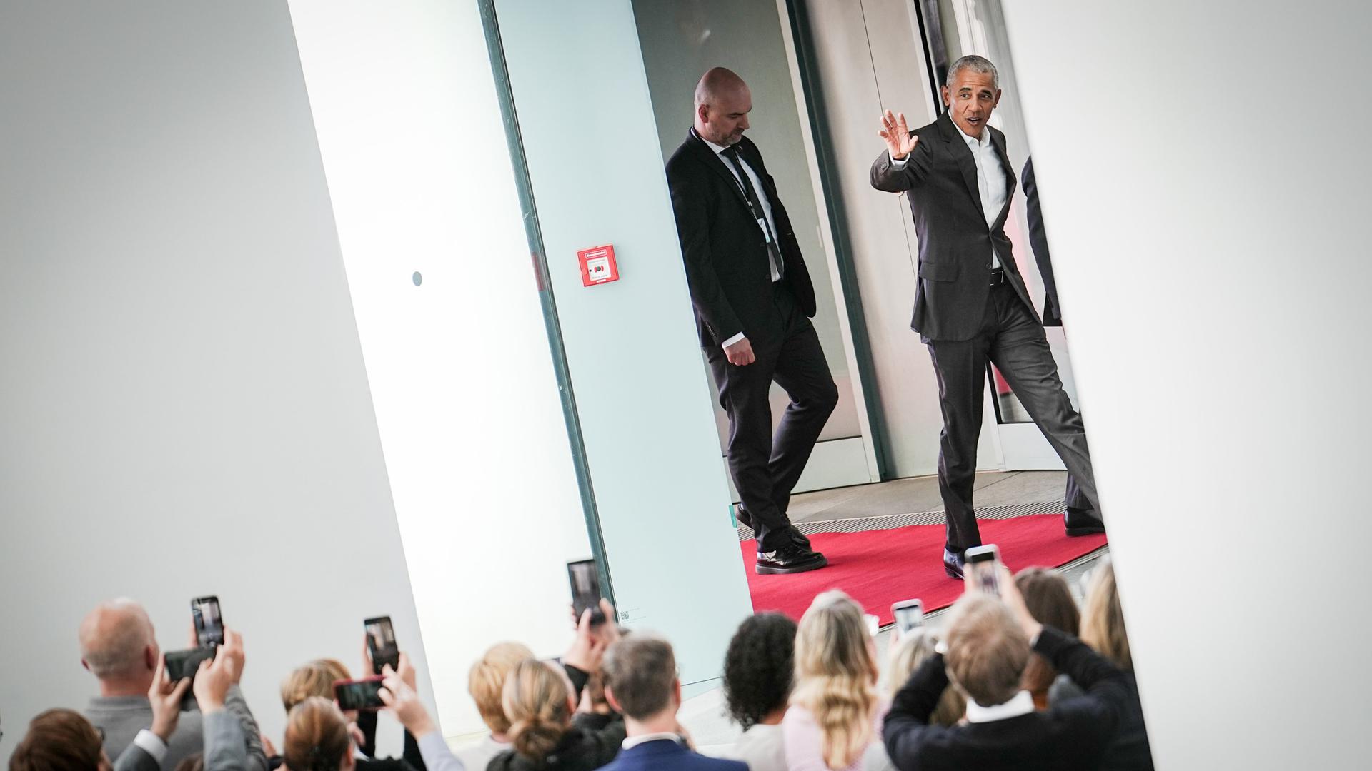 Der frühere US-Präsidenten Barack Obama (r) winkt im Bundeskanzleramt den Mitarbeitern des Kanzleramtes bei der Ankunft zu. Obama trifft dort Bundeskanzler Scholz.