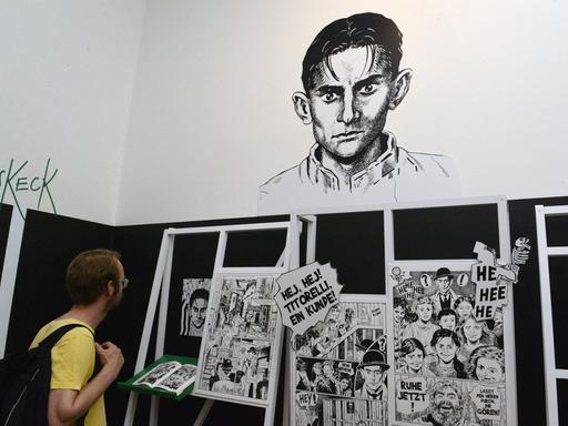 Ein junger Mann schaut sich Comic-Zeichnungen von Kafka in einer Ausstellung an.