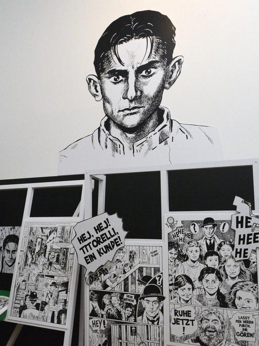 Ein junger Mann schaut sich Comic-Zeichnungen von Kafka in einer Ausstellung an.