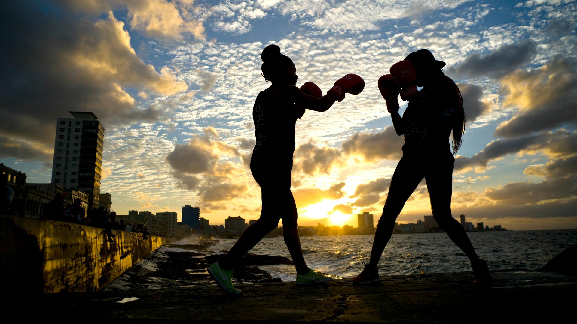 Die Boxerinnen Idamelys Moreno (links) und Legnis Cala trainieren während einer Fotosession auf der Uferpromenade von Havanna in Kuba. Es sind nur ihre Umrisse zu erkennen. Die Boxerinnen Idamelys Moreno (links) und Legnis Cala trainieren während einer Fotosession auf der Uferpromenade von Havanna in Kuba. Es sind nur ihre Umrisse zu erkennen.