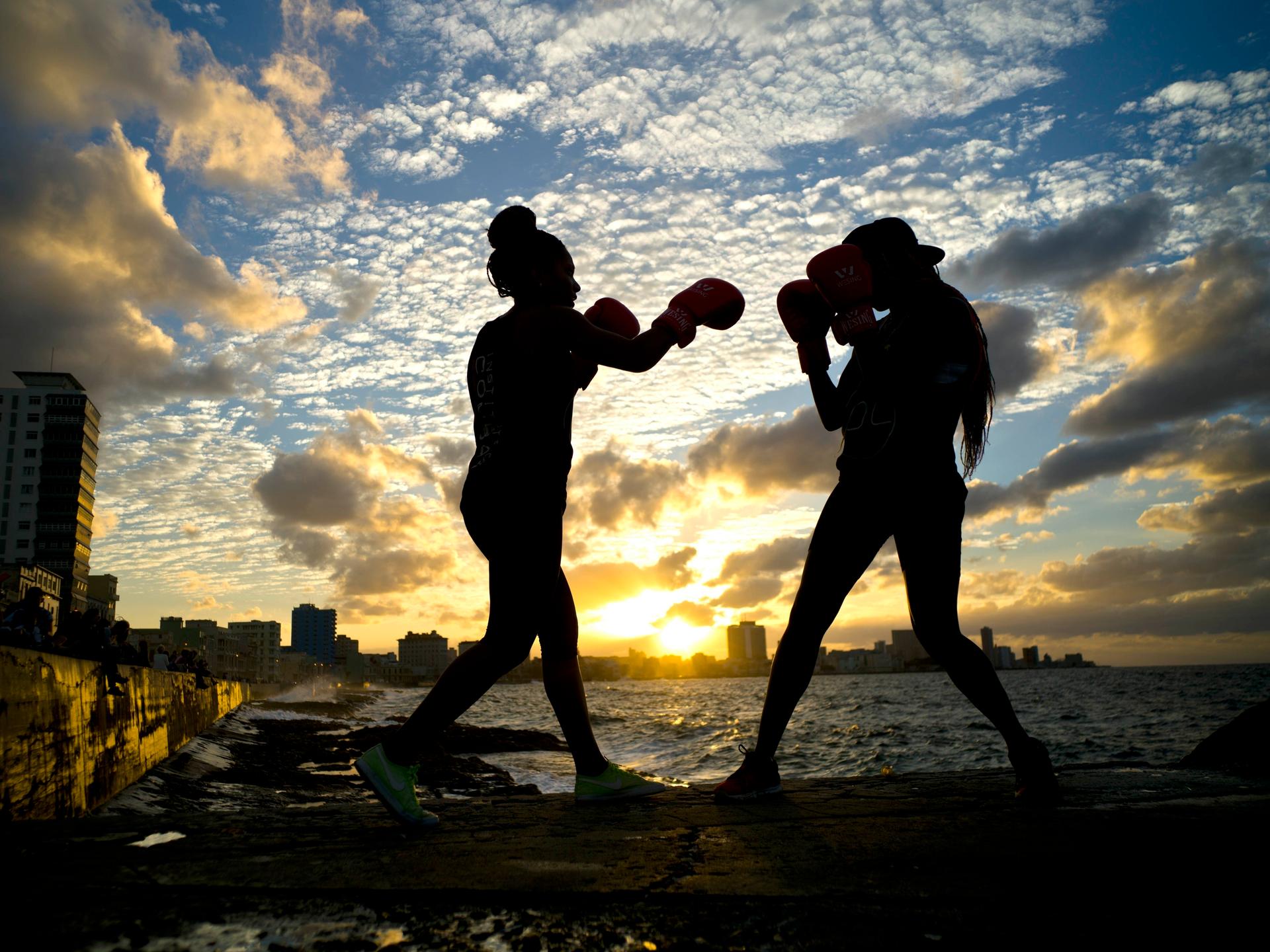 Die Boxerinnen Idamelys Moreno (links) und Legnis Cala trainieren während einer Fotosession auf der Uferpromenade von Havanna in Kuba. Es sind nur ihre Umrisse zu erkennen.
