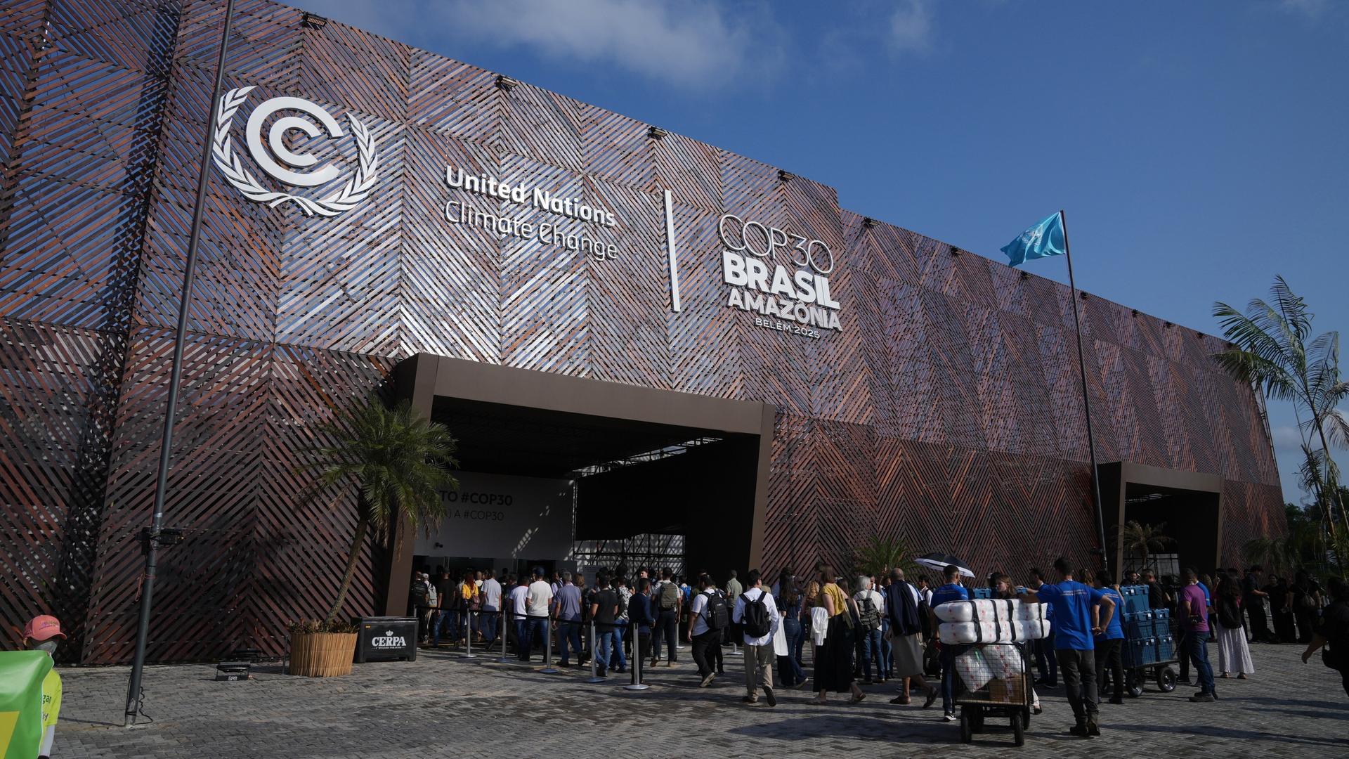 Teilnehmerinnen und Teilnehmer warten vor dem Eingang von der Welt-Klima-Konferenz.