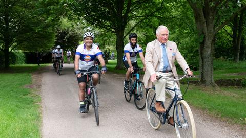 Prince Charles fährt bei einem Pressetermin Rad.