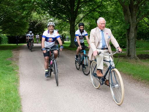 Prince Charles fährt bei einem Pressetermin Rad.