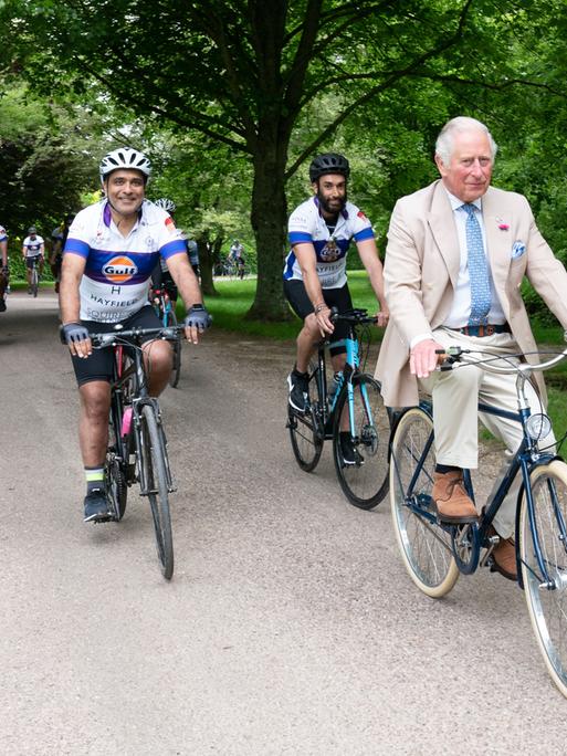 Prince Charles fährt bei einem Pressetermin Rad.