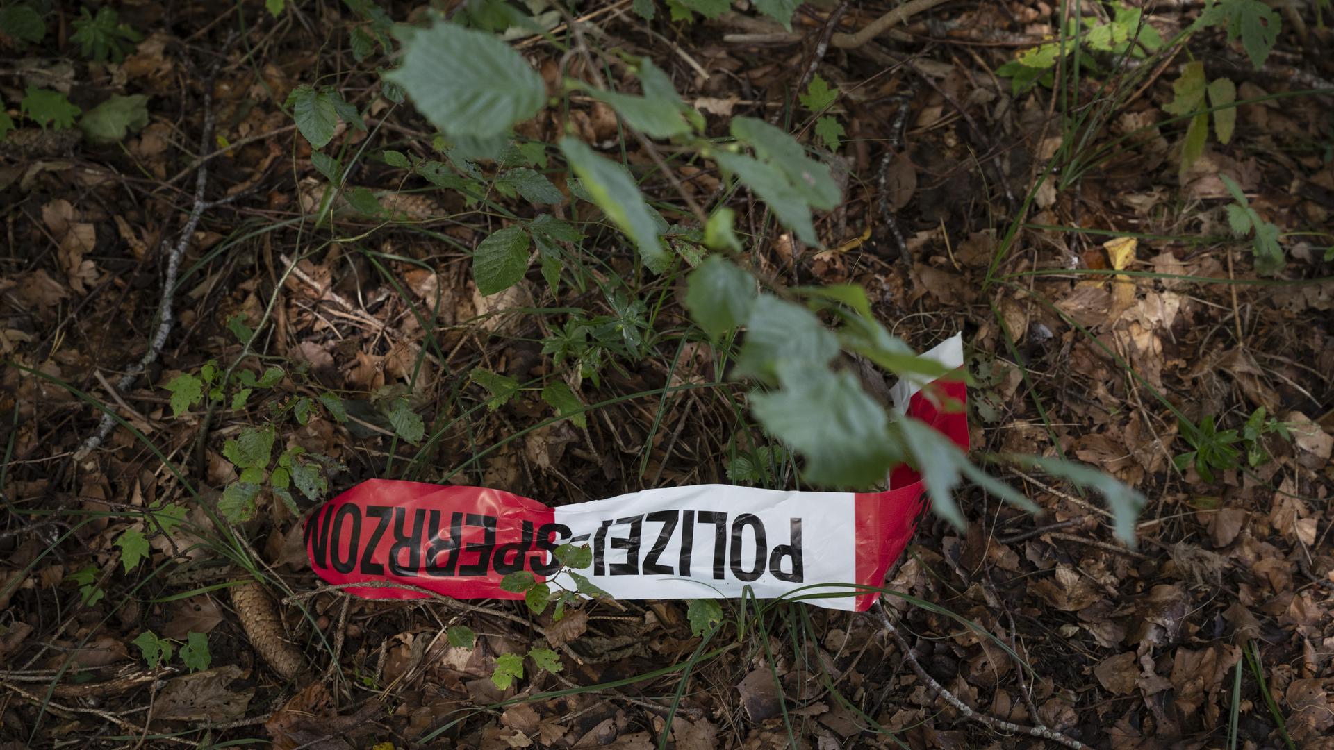 Ein Polizeiabsperrband liegt auf dem Waldboden im Zusammenhang mit dem ersten Einsatz der Todeskapsel Sarco. 