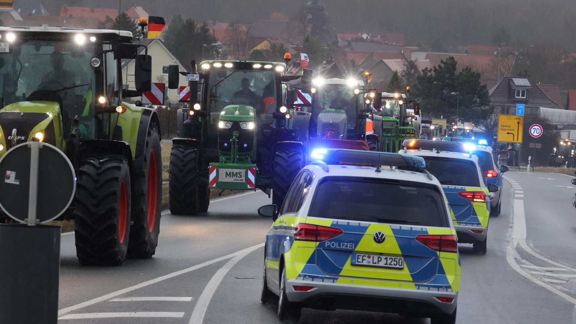 Polizeifahrzeuge begleiten Landwirte, die mit ihren Traktoren über die Bundesstraße 7 fahren. Mit der Aktion wollen die Landwirte gegen die derzeitige Agrarpolitik der Bundesregierung demonstrieren.