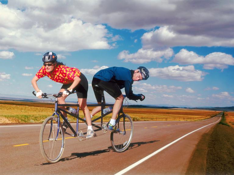 Eine Fahrradfahrerin und ein Fahrradfahrer steuern auf einem Tandem in unterschiedliche Richtungen. (Symbolbild)