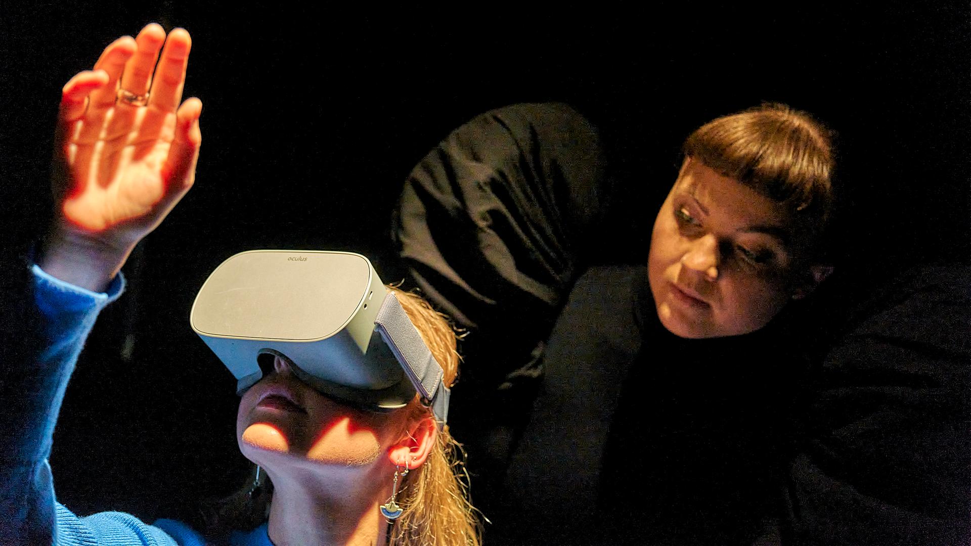 Eine Zuschauerin von "Berlau" im BE trägt eine VR-Brille. Hinter ihr eine Schauspielerin mit schwarzen Engelsflügeln.