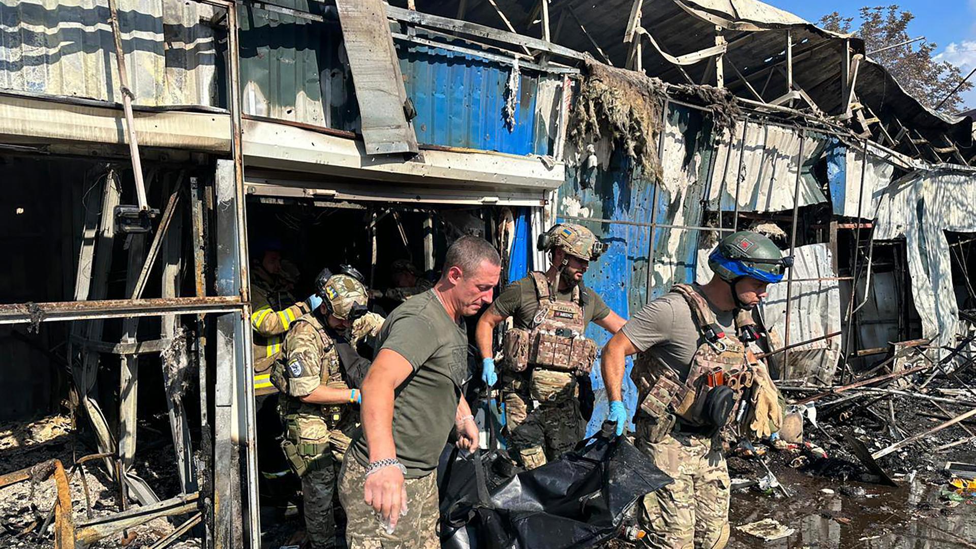 Mehrere Soldaten tragen einen Leichensack aus einem zerstörten Gebäude. Mehrere Soldaten tragen einen Leichensack aus einem zerstörten Gebäude.