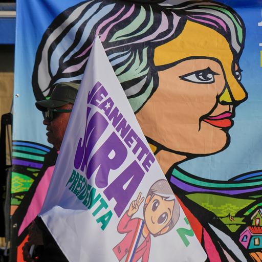 Vor einem großen Plakat mit einer stilisierten Darstellung Jaras sieht man den oberen Teil einer Fahne ebenfalls mit dem Namen und einer Darstellung Jaras.