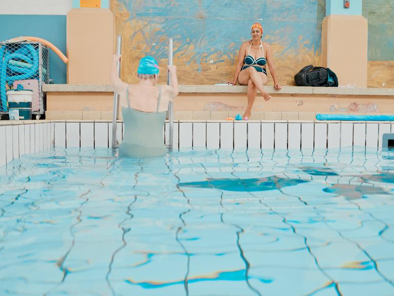 Frauen nach Wassergymnastik und Schwimmen bei Aussteigen aus deinem Schwimmbecken in einer Schwimmhalle.